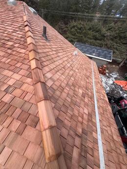 view of newly installed cedar shake of left roof slope and ridge cap showns