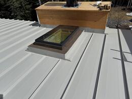 flashed skylight and chimney.. a grey metal roof installation process in Calgary, AB